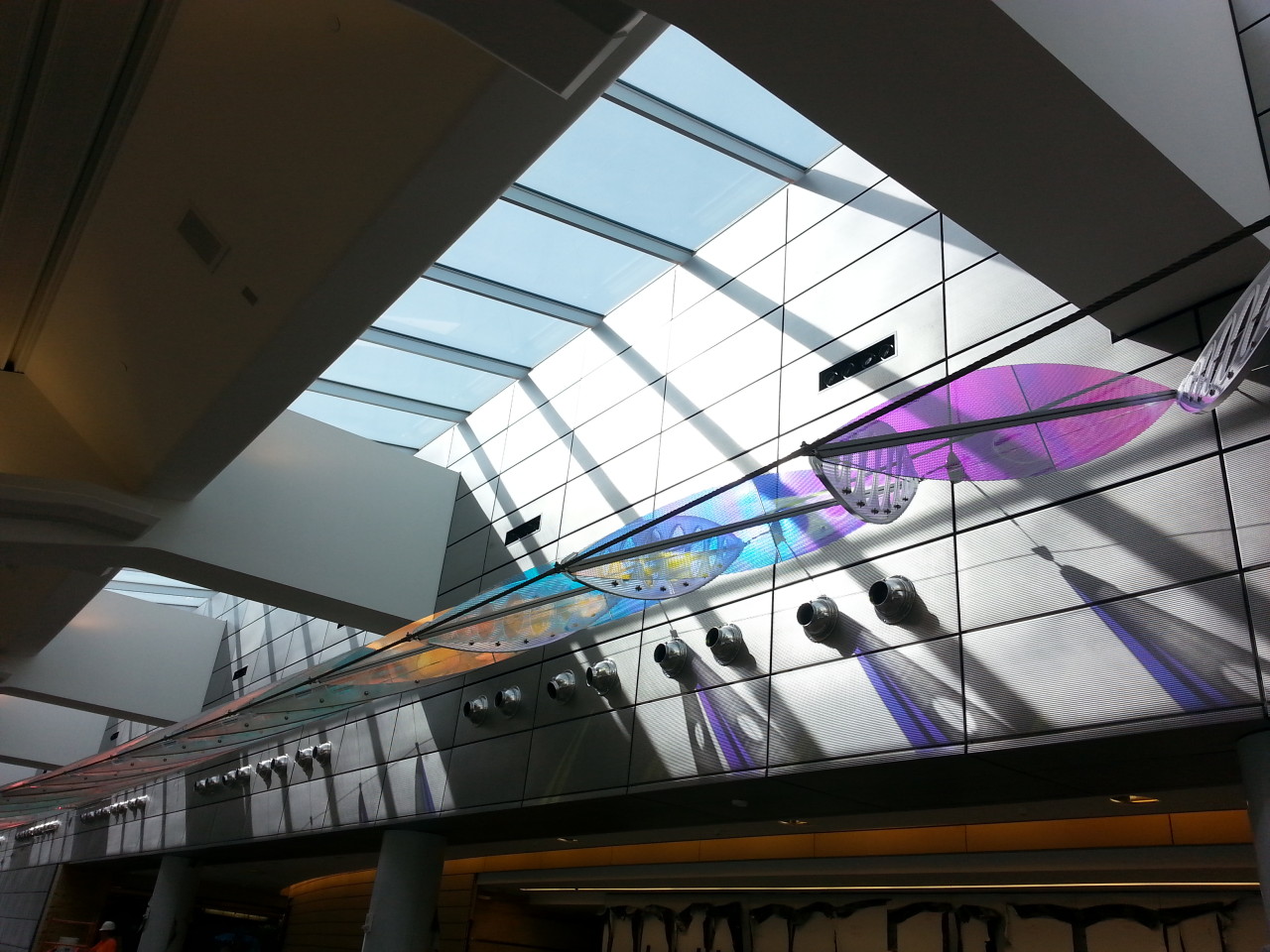 Ed Carpenter’s Wichita Dwight D. Eisenhower National Airport signature sculpture Aloft delights travelers with colorful laminated safety dichroic glass above as well as producing ever changing color patterns on the walls. | Image 11 | Ed Carpenter, Artist